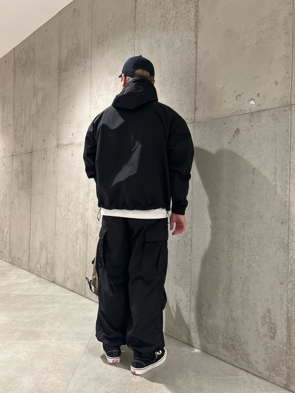 ホワイト系のTシャツ/カットソー、ベージュ系のバックパック/リュック、ブラック系のスニーカーを着用したメンズの春コーディネートの3枚目の写真