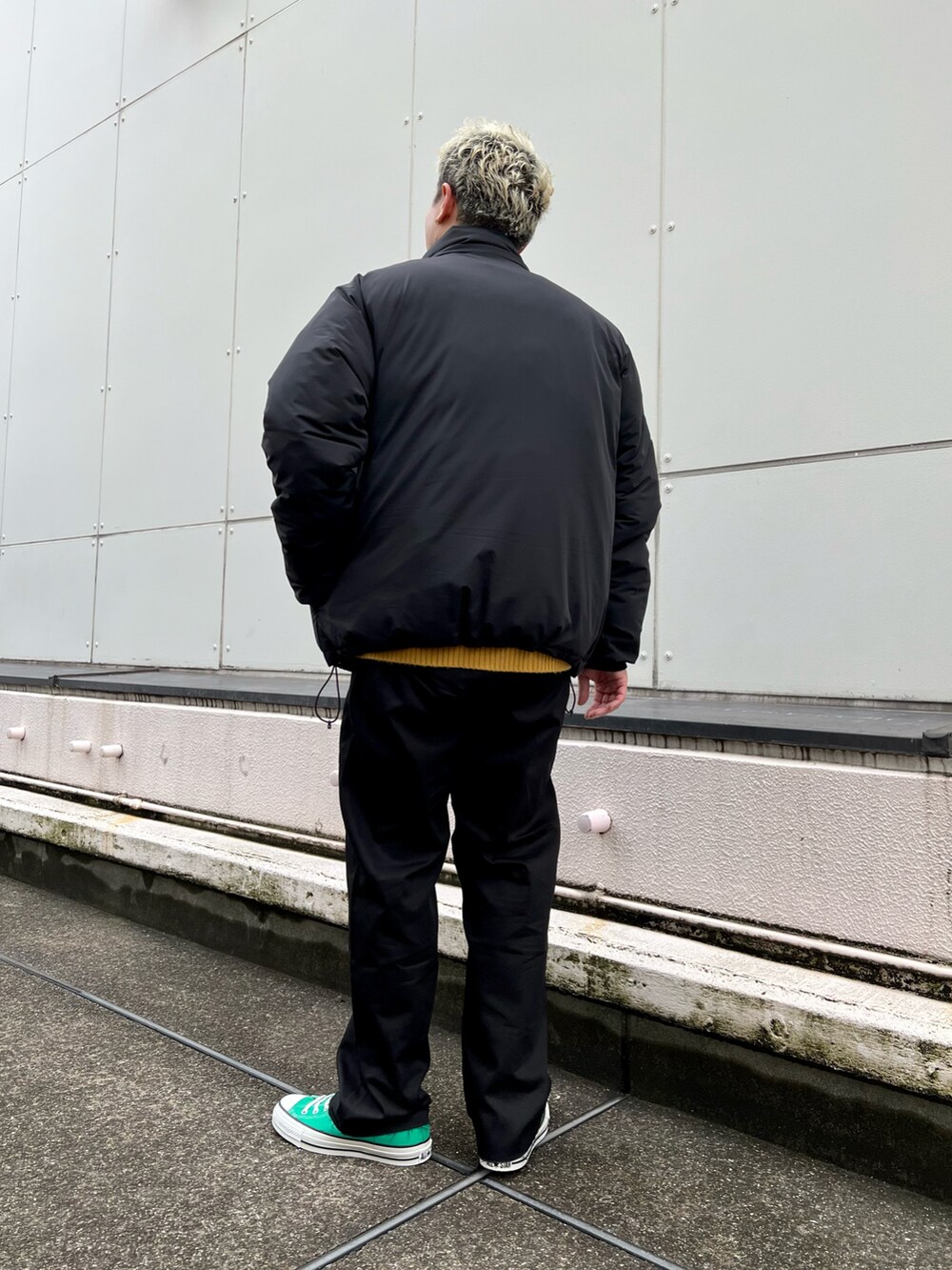 ブラック系のダウンジャケット/コート、イエロー系のカーディガン/ボレロ、ブラック系のチノパンツを着用したメンズの冬コーディネートの5枚目の写真