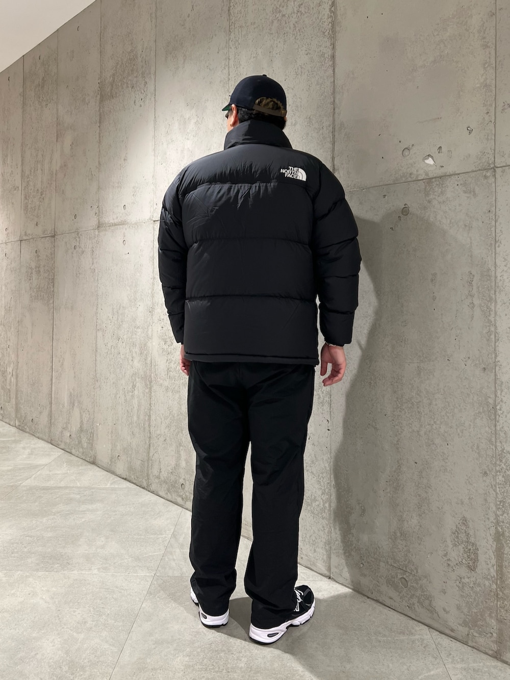 ブラック系のダウンジャケット/コート、ブラック系のパンツ、ブラック系のスニーカーを着用したメンズの秋コーディネートの3枚目の写真