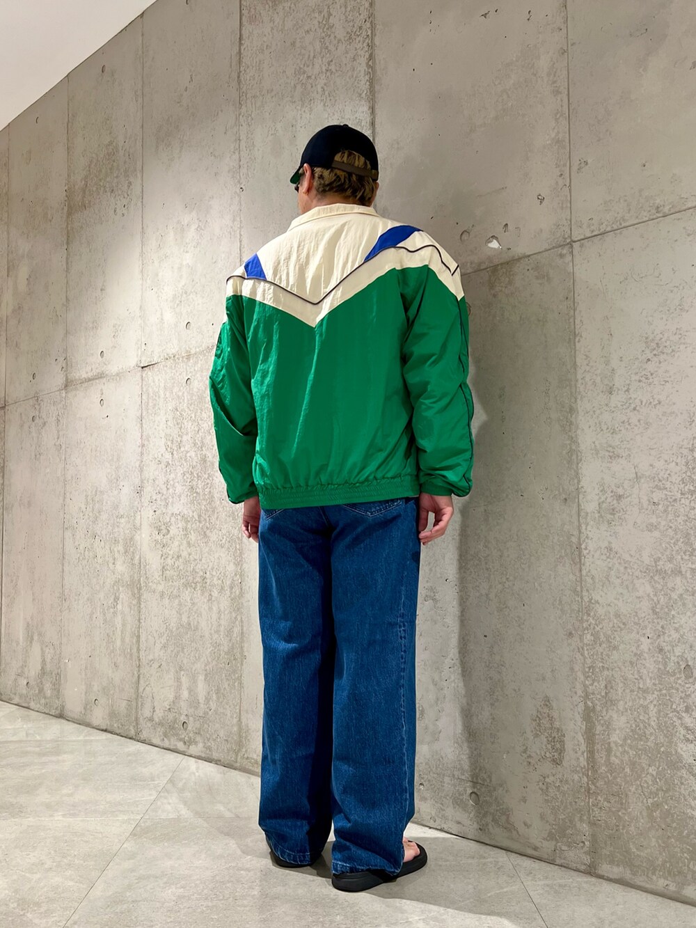 グリーン系のナイロンジャケット、ベージュ系のTシャツ/カットソー、ブルー系のデニムパンツを着用したメンズの夏コーディネートの3枚目の写真