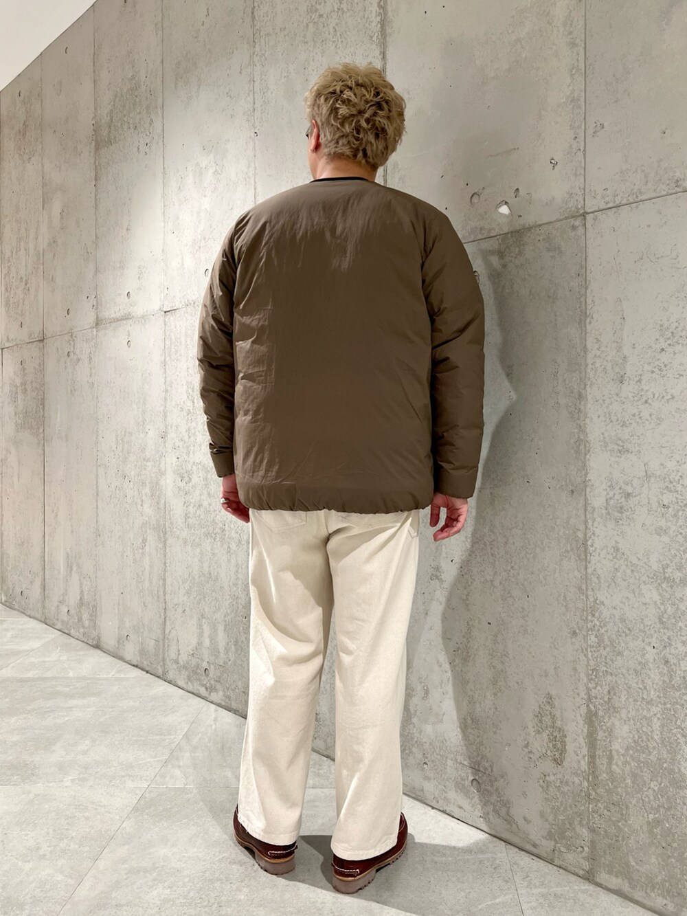 ブラウン系のダウンジャケット/コート、レッド系のモカシン/デッキシューズ、ホワイト系のデニムパンツを着用したメンズの秋コーディネートの4枚目の写真