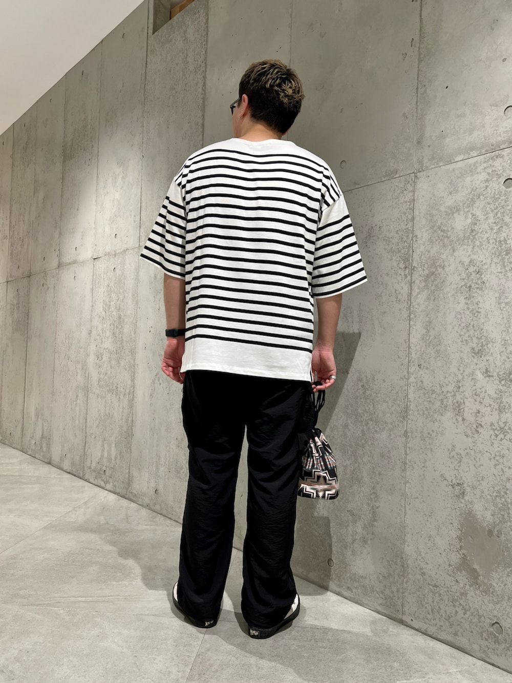 ブラック系のショルダーバッグ、ホワイト系のスニーカー、ブラック系のその他パンツを着用したメンズの夏コーディネートの4枚目の写真