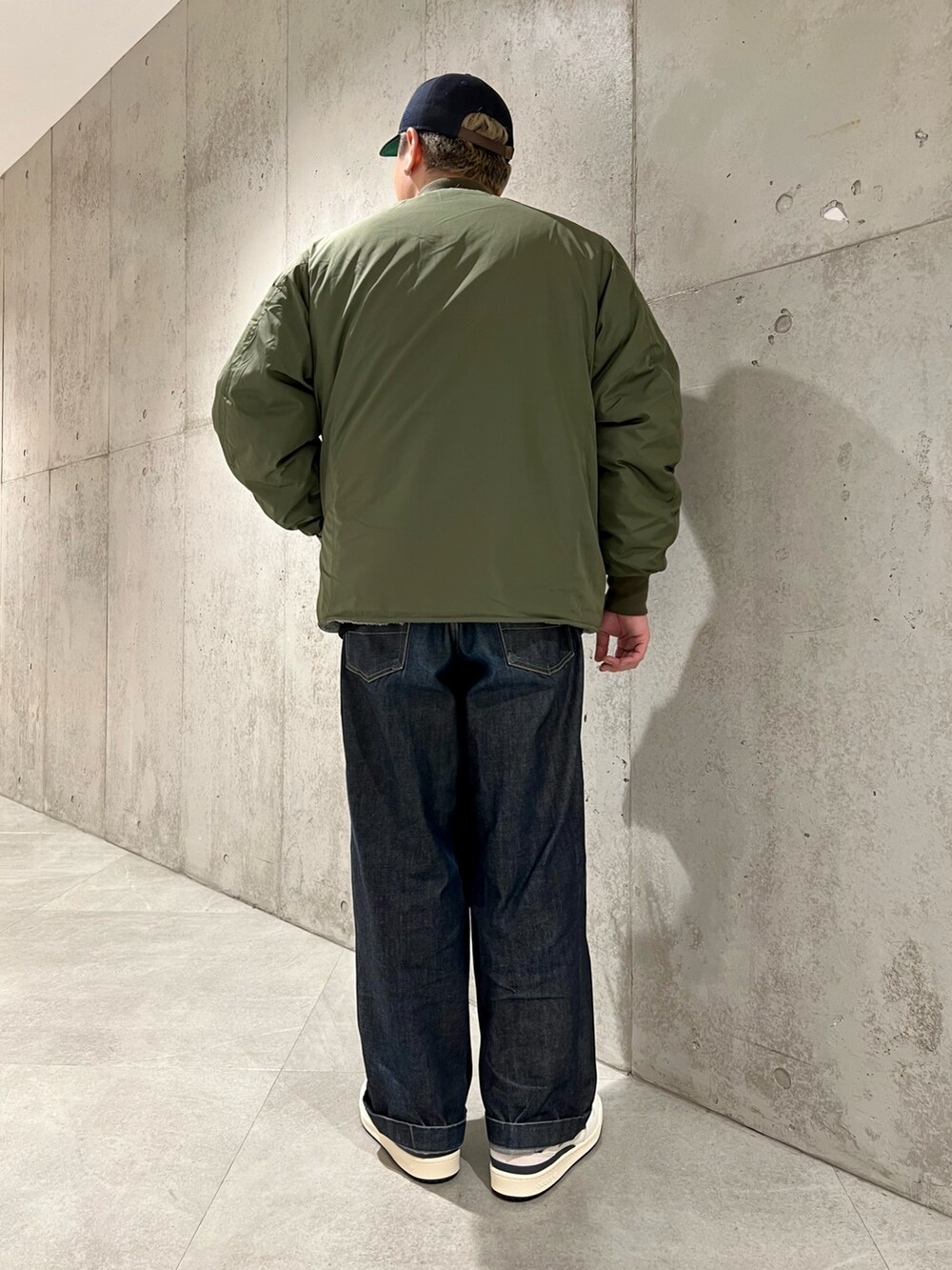 グリーン系のブルゾン、ブルー系のデニムパンツ、ホワイト系のスニーカーを着用したメンズの秋コーディネートの3枚目の写真