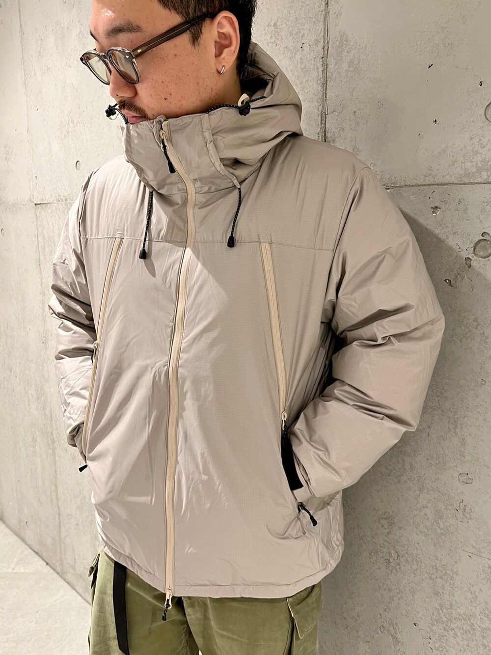 グリーン系のカーゴパンツ、ブラック系のブーツ、ベージュ系のダウンジャケット/コートを着用したメンズの秋コーディネートの2枚目の写真