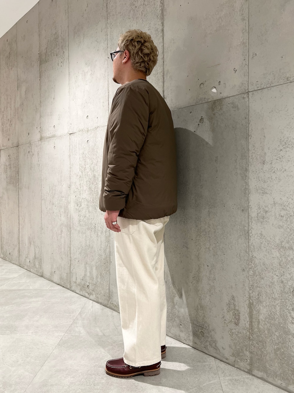 ブラウン系のダウンジャケット/コート、レッド系のモカシン/デッキシューズ、ホワイト系のデニムパンツを着用したメンズの秋コーディネートの3枚目の写真