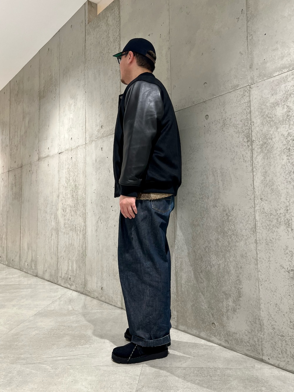 ブラック系のブルゾン、ブラック系のブーツ、グリーン系のニット/セーターを着用したメンズの冬コーディネートの2枚目の写真