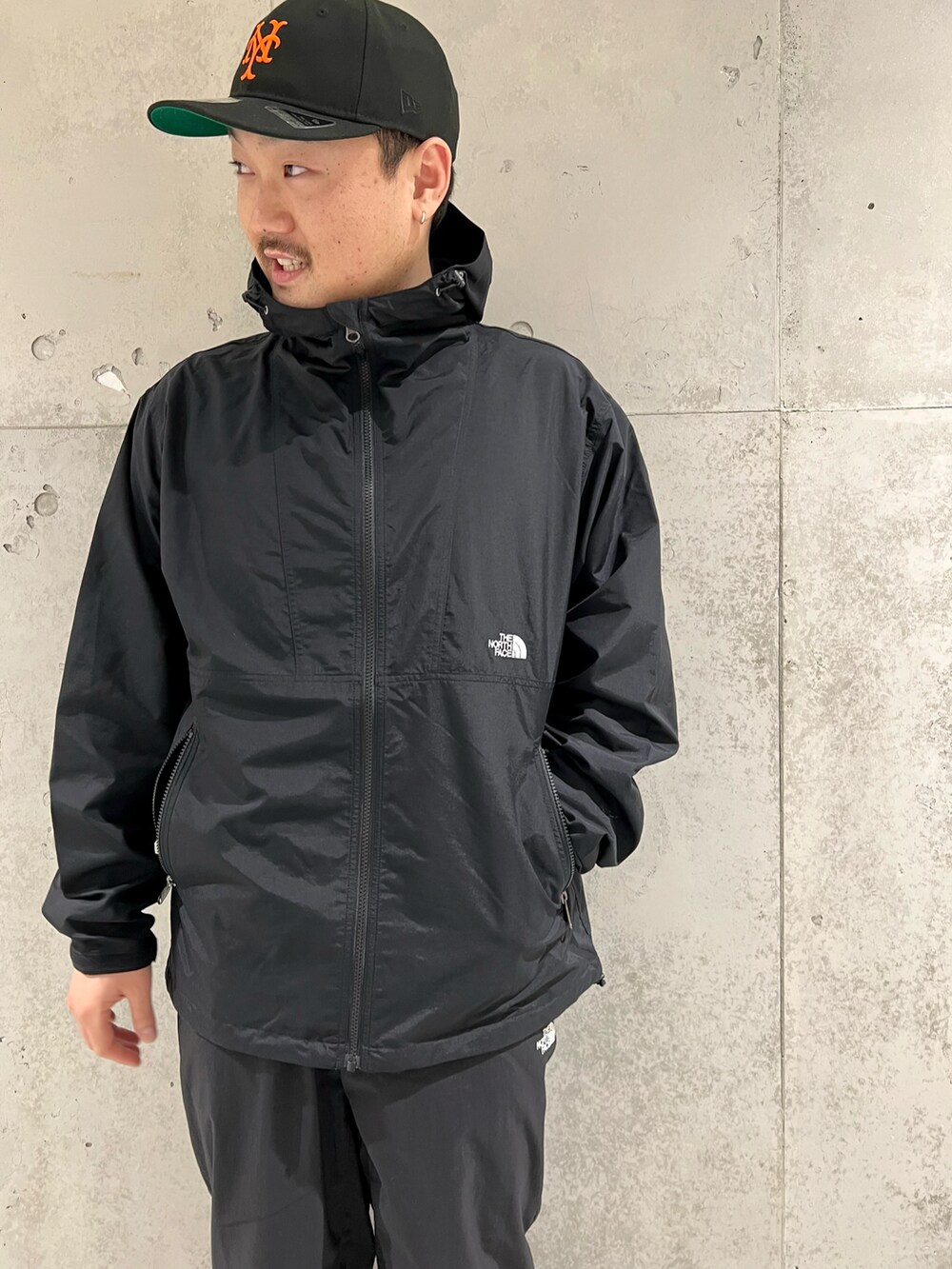 ブラック系のマウンテンパーカー、ホワイト系のTシャツ/カットソー、ブラック系のスニーカーを着用したメンズの春コーディネートの3枚目の写真