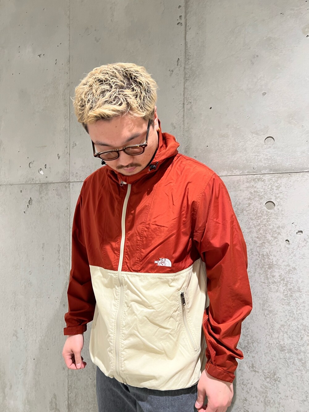 レッド系のナイロンジャケット、ブラック系のデニムパンツ、レッド系のスニーカーを着用したメンズの春コーディネートの4枚目の写真