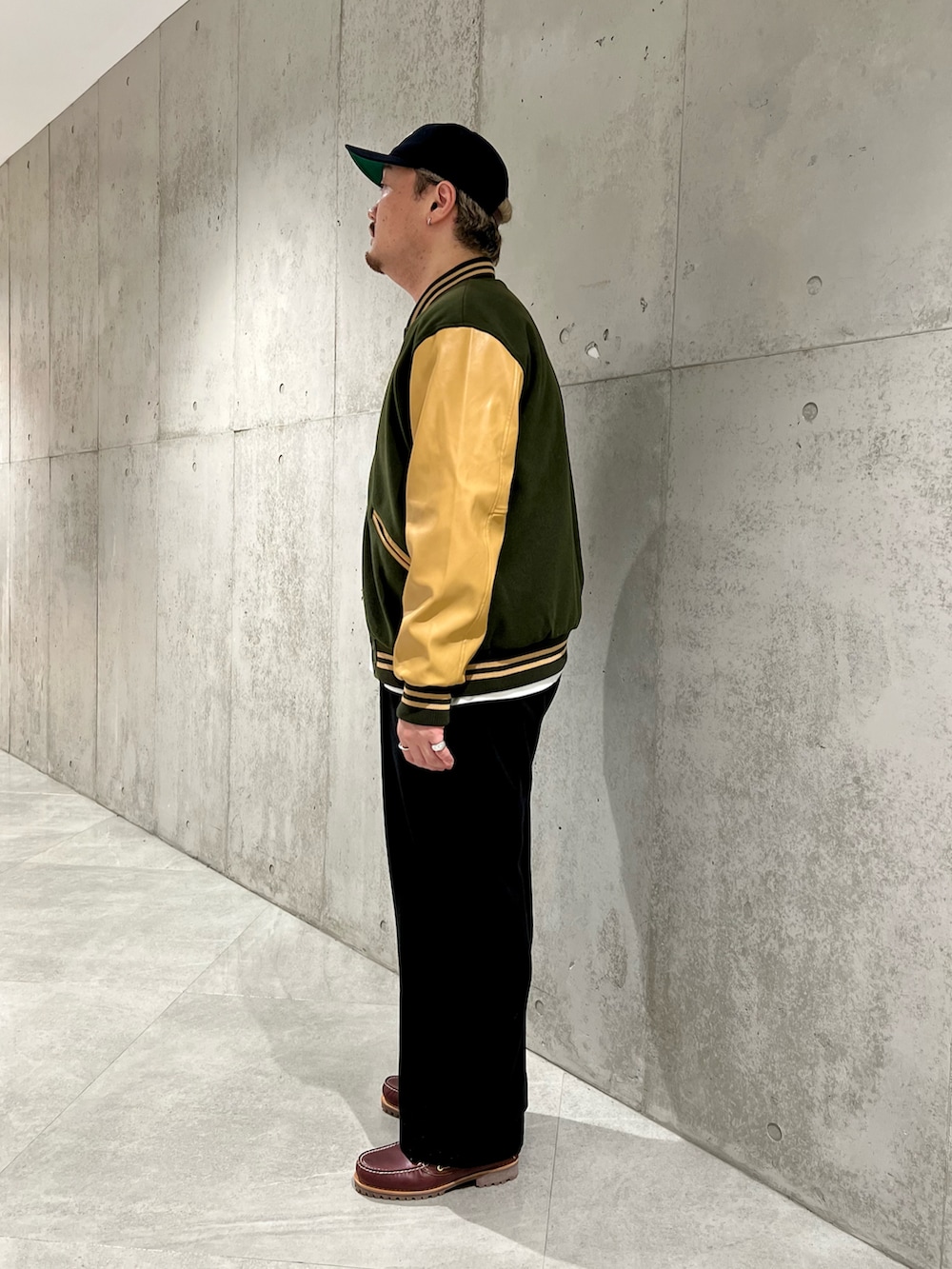 グリーン系のスタジャン、ホワイト系のTシャツ/カットソー、ブラック系のその他パンツを着用したメンズの秋コーディネートの3枚目の写真