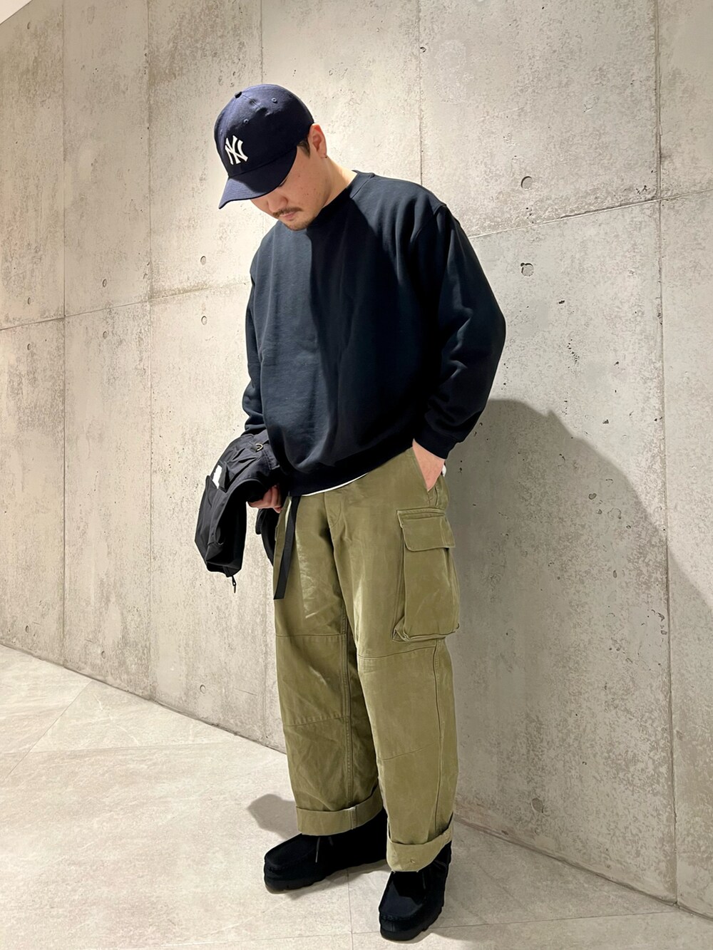 ブラック系のベスト、グリーン系のカーゴパンツ、ブラック系のブーツを着用したメンズの冬コーディネートの3枚目の写真