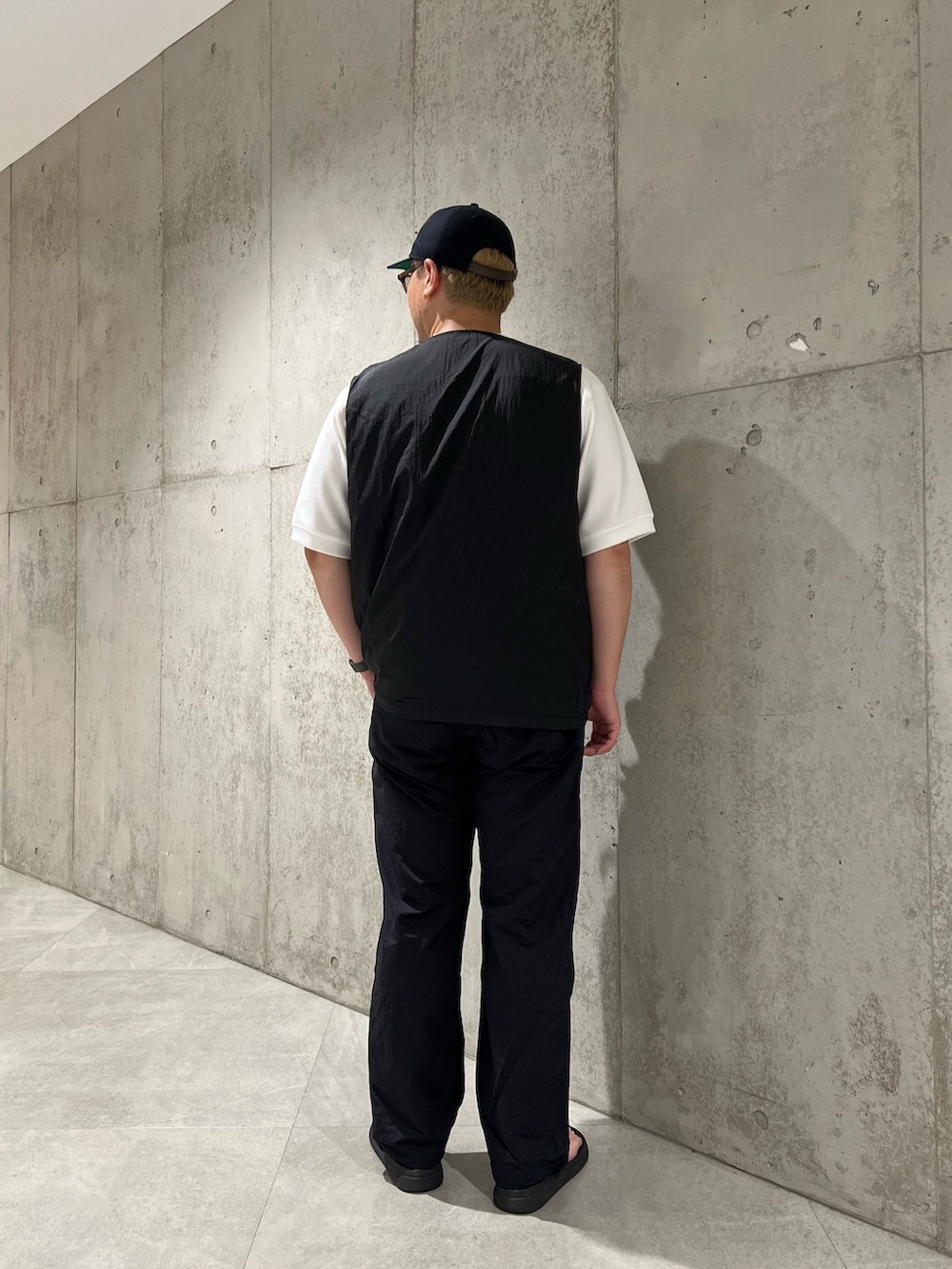 ホワイト系のTシャツ/カットソー、ブラック系のベスト、ブラック系のサンダルを着用したメンズの夏コーディネートの4枚目の写真