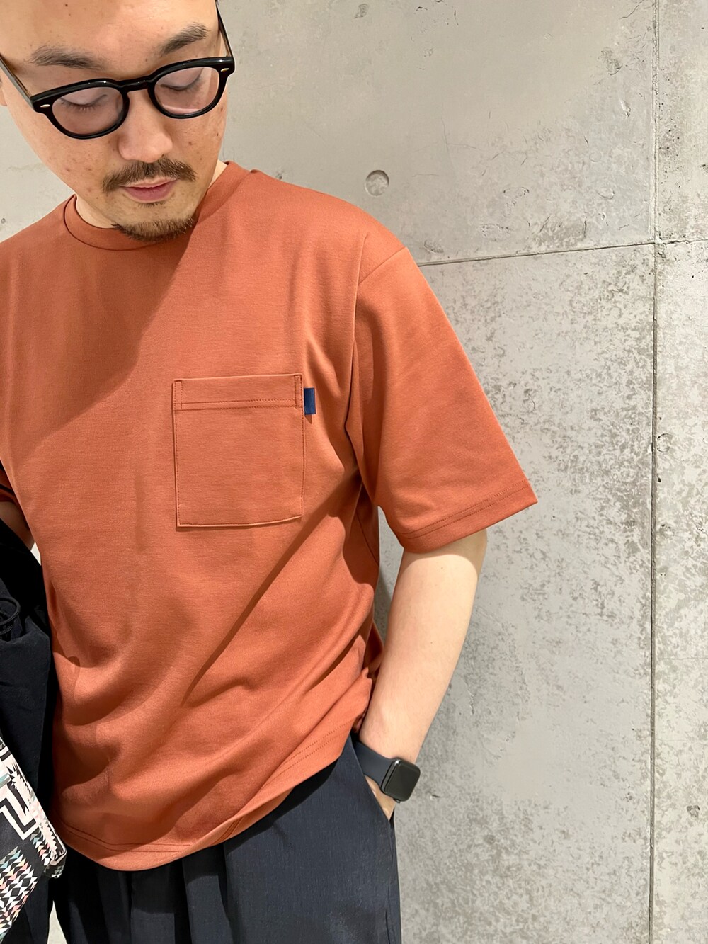 ホワイト系のスニーカー、ブラック系のシャツ/ブラウス、オレンジ系のTシャツ/カットソーを着用したメンズの夏コーディネートの2枚目の写真