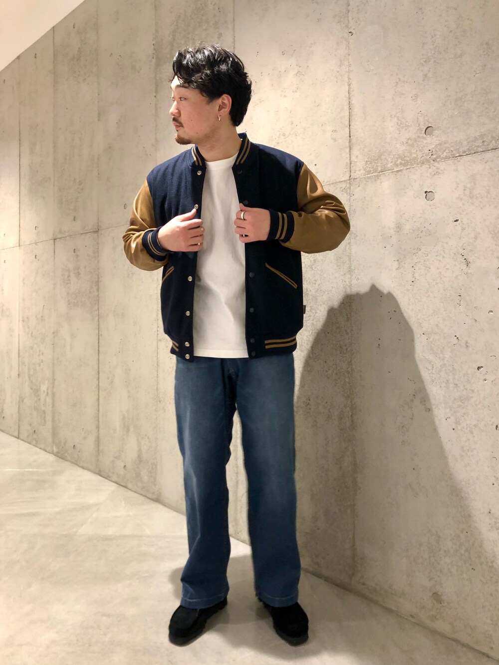 ホワイト系のTシャツ/カットソー、ブルー系のデニムパンツ、ブラック系のブーツを着用したメンズの秋コーディネートの2枚目の写真