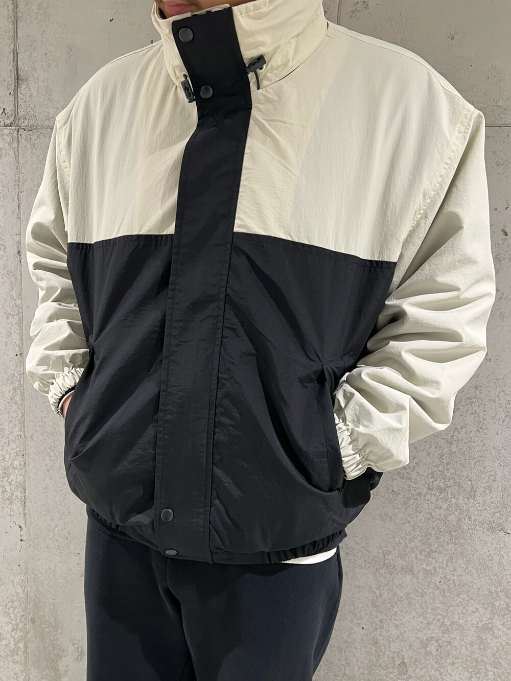 ブラック系のナイロンジャケット、ベージュ系のスニーカー、ブラック系のスウェットを着用したメンズの春コーディネートの5枚目の写真