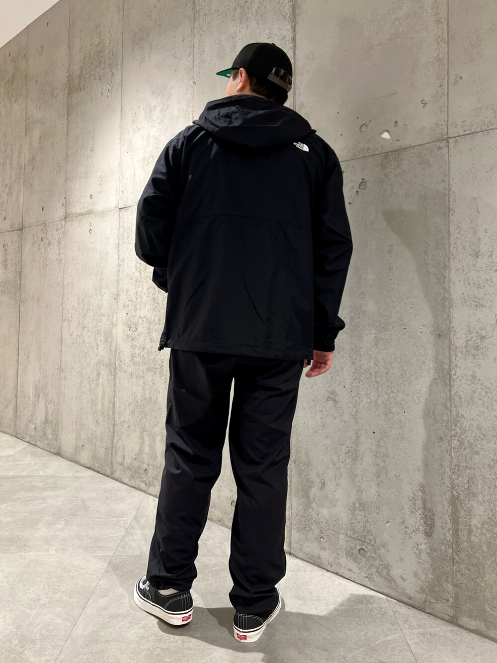 ブラック系のマウンテンパーカー、ホワイト系のTシャツ/カットソー、ブラック系のスニーカーを着用したメンズの春コーディネートの5枚目の写真