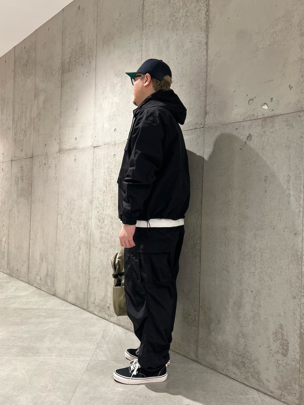 ホワイト系のTシャツ/カットソー、ベージュ系のバックパック/リュック、ブラック系のスニーカーを着用したメンズの春コーディネートの2枚目の写真