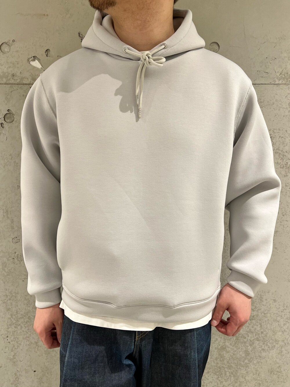 ブラック系のカーディガン/ボレロ、グレー系のパーカー、ブルー系のデニムパンツを着用したメンズの春コーディネートの5枚目の写真