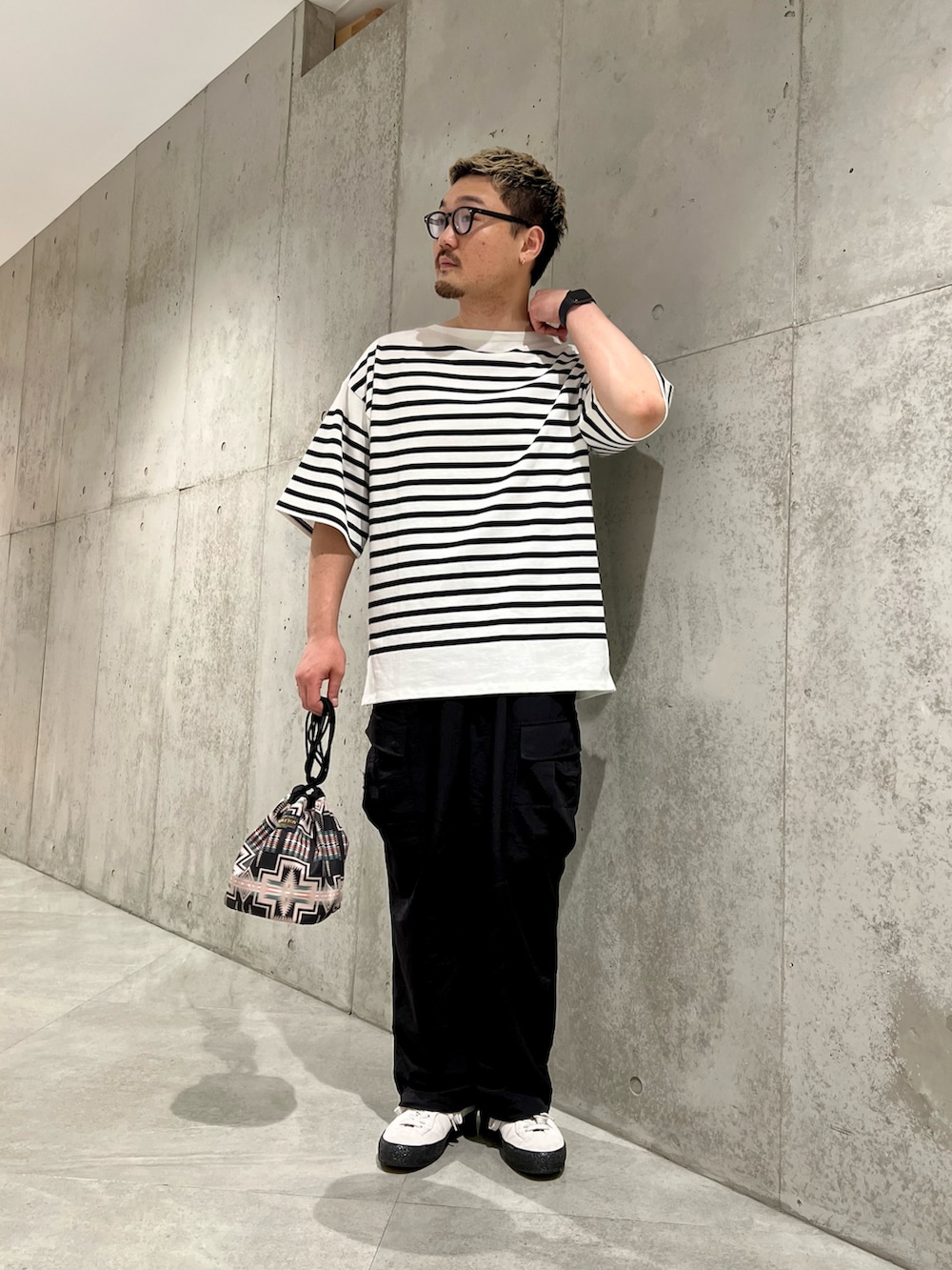 ブラック系のショルダーバッグ、ホワイト系のスニーカー、ブラック系のその他パンツを着用したメンズの夏コーディネートの2枚目の写真