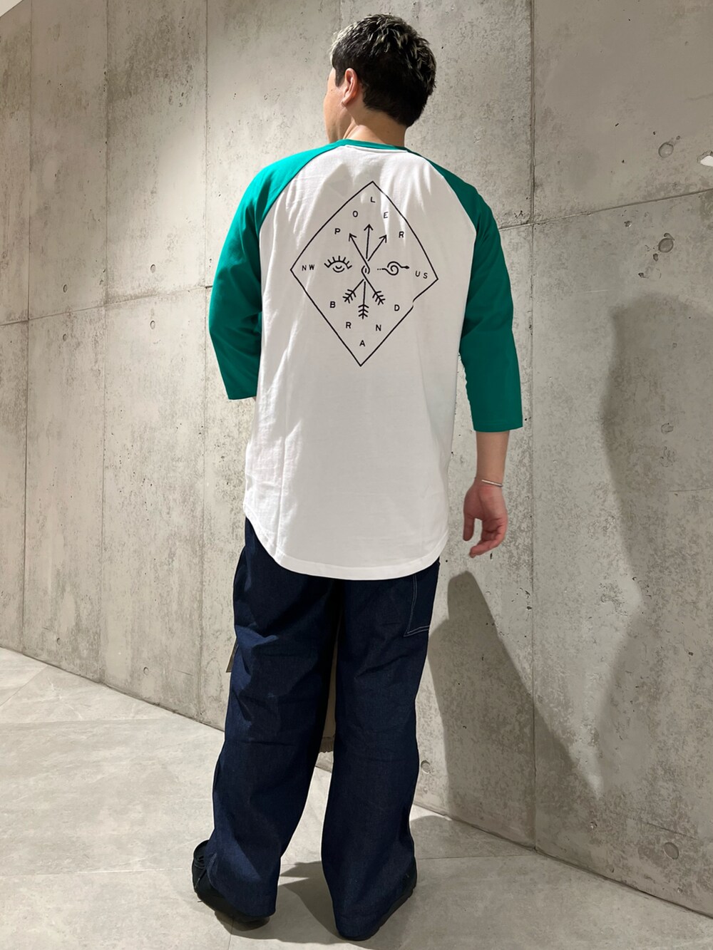 ホワイト系のマウンテンパーカー、グリーン系のTシャツ/カットソー、ブラック系のブーツを着用したメンズの春コーディネートの5枚目の写真