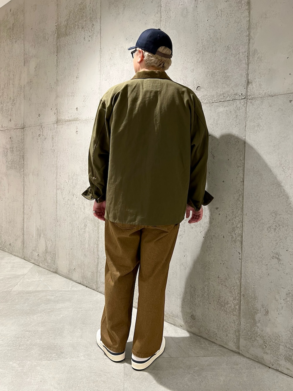 グリーン系のカバーオール、ベージュ系のTシャツ/カットソー、ブラウン系のデニムパンツを着用したメンズの秋コーディネートの3枚目の写真