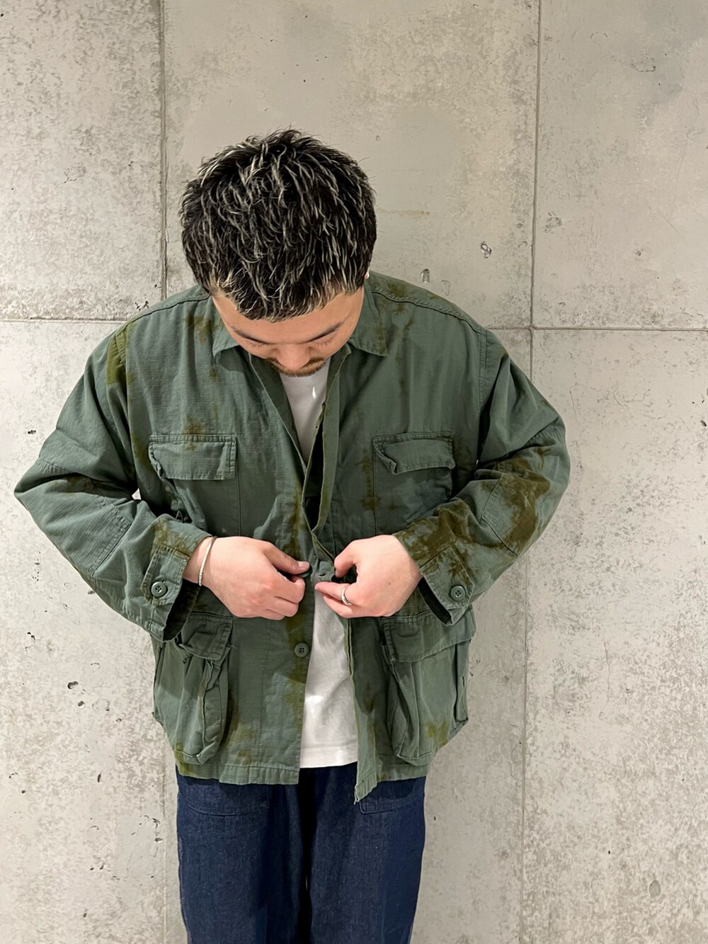 ブルー系のデニムパンツ、ブラック系のブーツ、ブルー系のミリタリージャケットを着用したメンズの春コーディネートの2枚目の写真