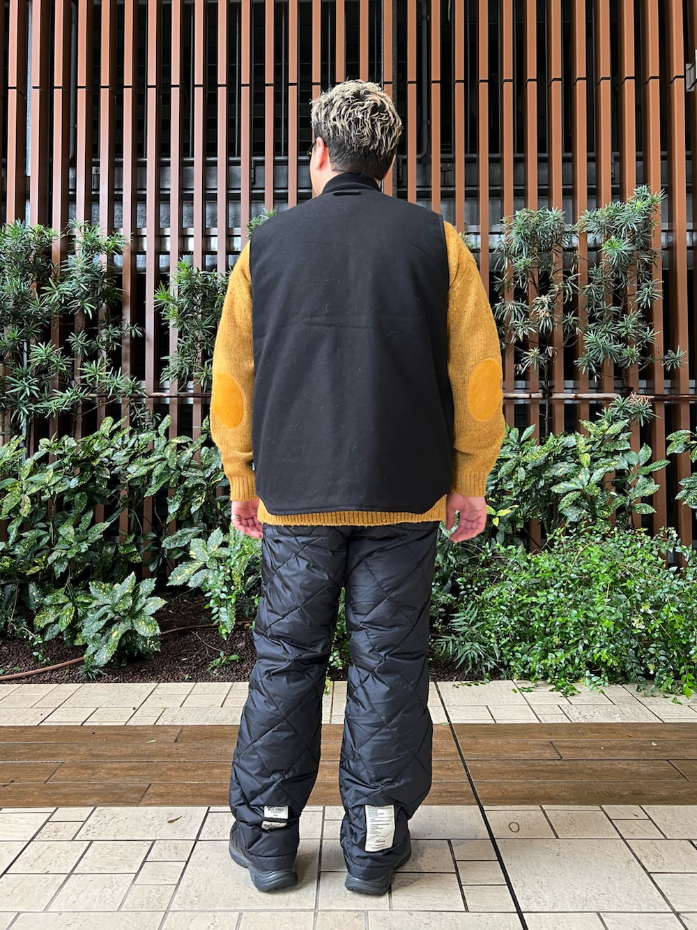 ブラック系のベスト、イエロー系のニット/セーター、ブラック系のその他パンツを着用したメンズの冬コーディネートの4枚目の写真
