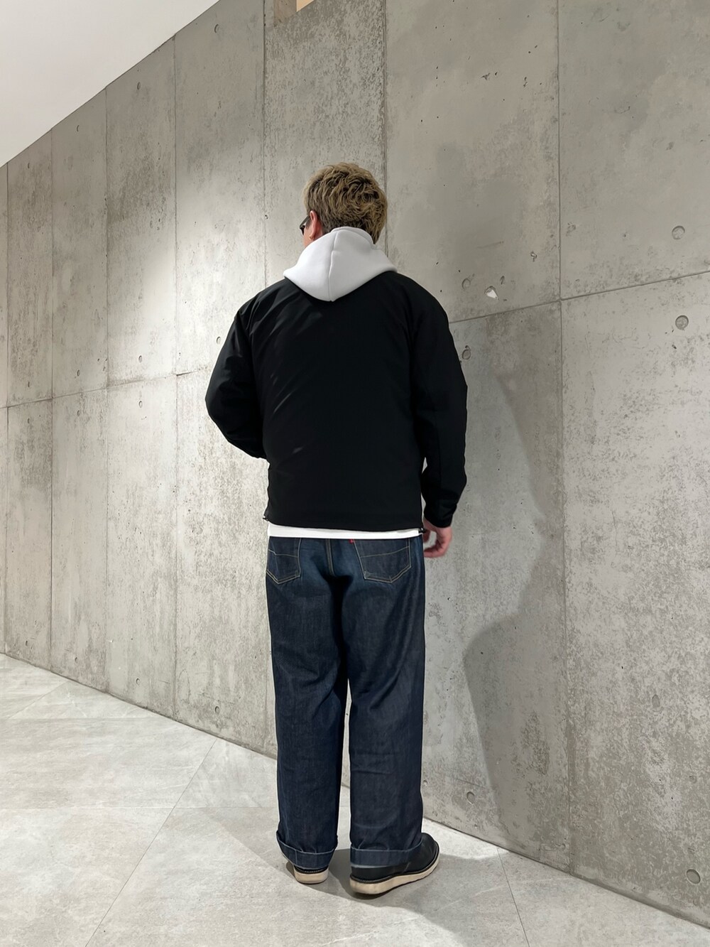 ブラック系のカーディガン/ボレロ、グレー系のパーカー、ブルー系のデニムパンツを着用したメンズの春コーディネートの3枚目の写真