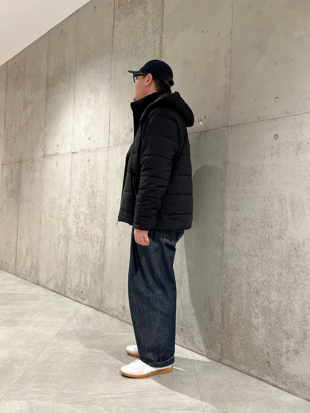 ブラック系のダウンジャケット/コート、ブラック系のTシャツ/カットソー、ホワイト系のスニーカーを着用したメンズの冬コーディネートの2枚目の写真