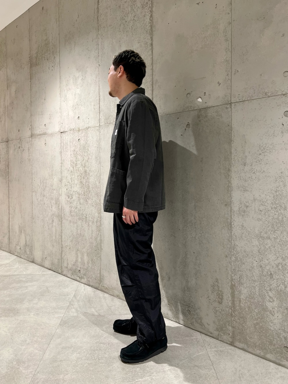 ブラック系のカバーオール、ホワイト系のTシャツ/カットソー、ブラック系のブーツを着用したメンズの春コーディネートの3枚目の写真