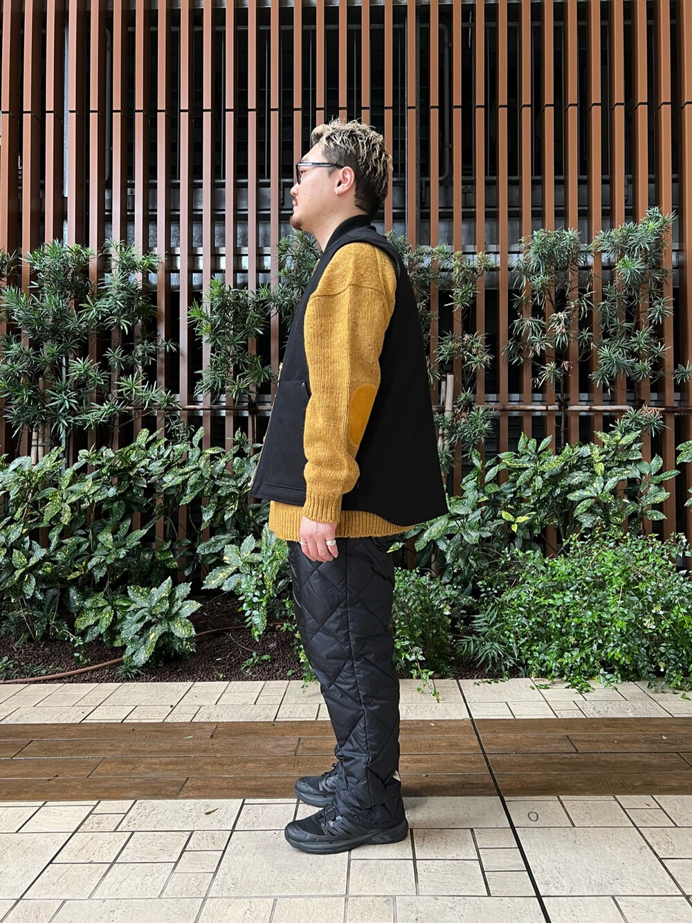 ブラック系のベスト、イエロー系のニット/セーター、ブラック系のその他パンツを着用したメンズの冬コーディネートの3枚目の写真