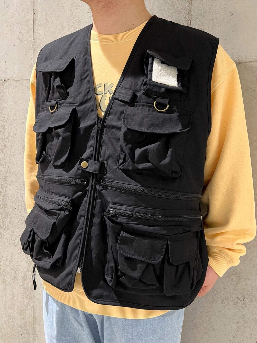 ブラック系のベスト、ブルー系のデニムパンツ、ブラック系のブーツを着用したメンズの春コーディネートの2枚目の写真