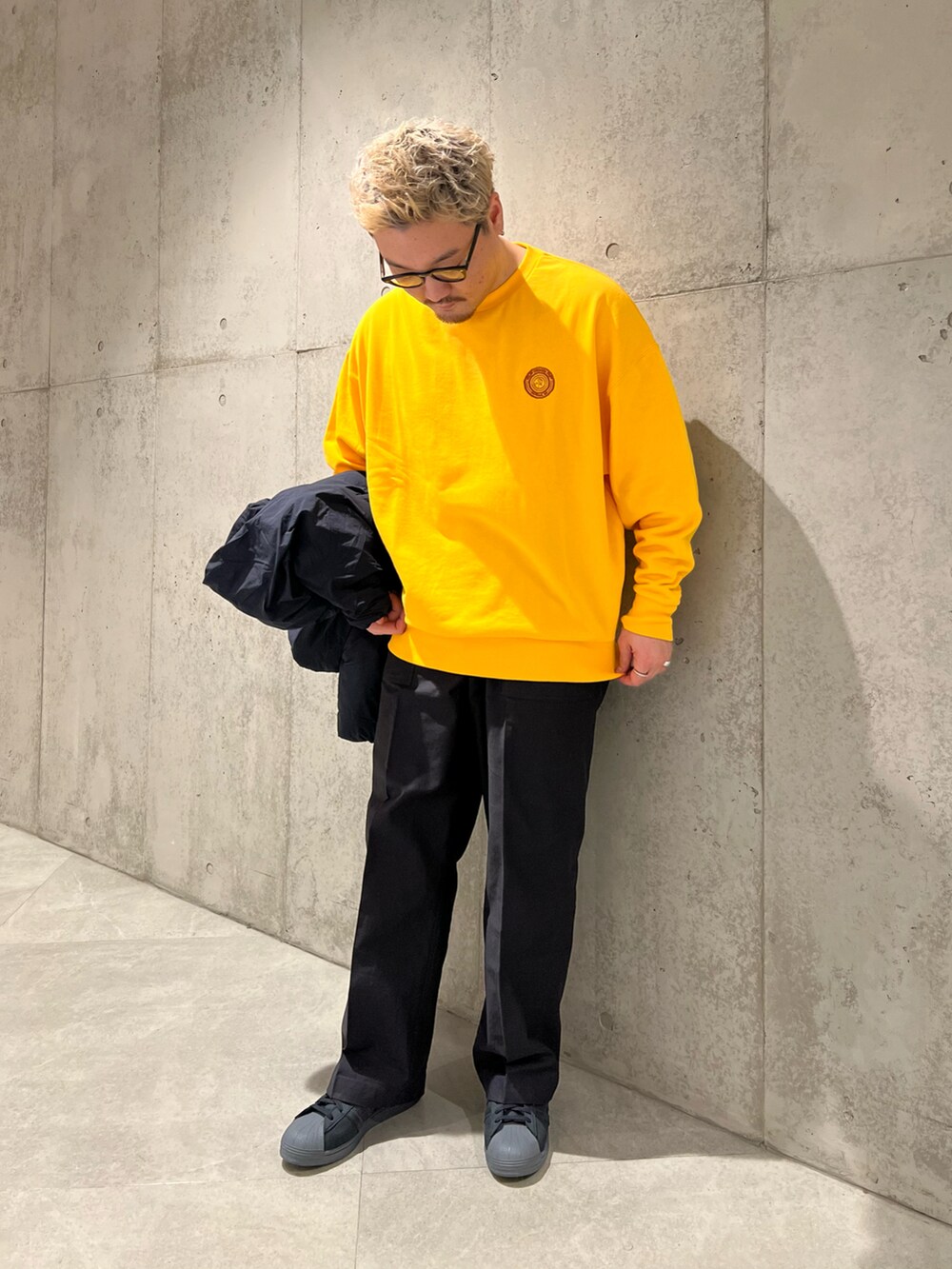 ブラック系のその他パンツ、ブラック系のダウンジャケット/コート、イエロー系のスウェットを着用したメンズの秋コーディネートの4枚目の写真