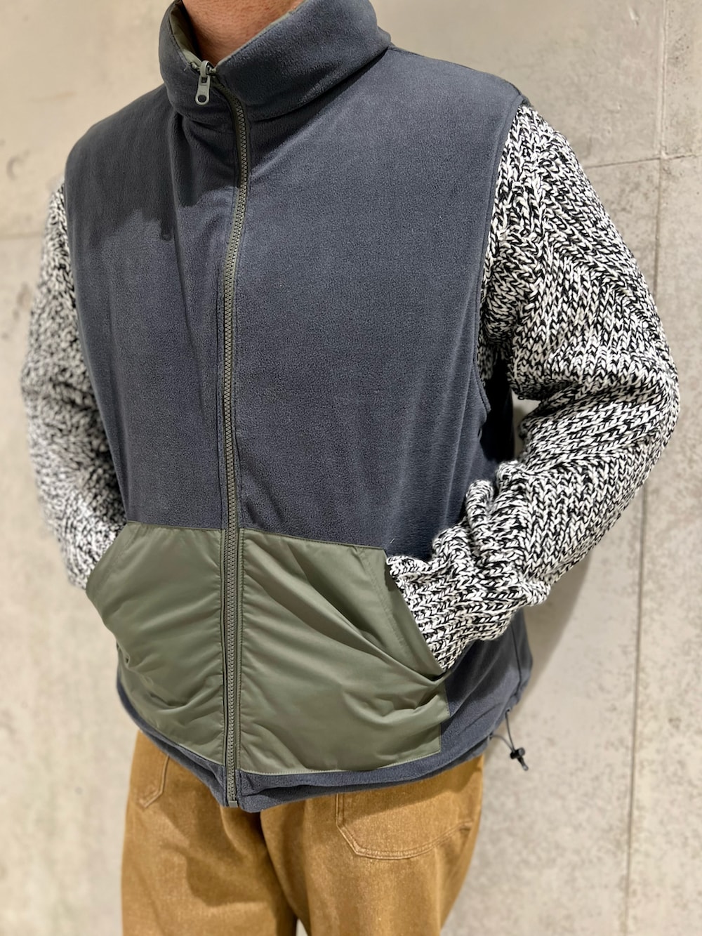 レッド系のモカシン/デッキシューズ、ブラウン系のデニムパンツ、グリーン系のダウンベストを着用したメンズの秋コーディネートの4枚目の写真