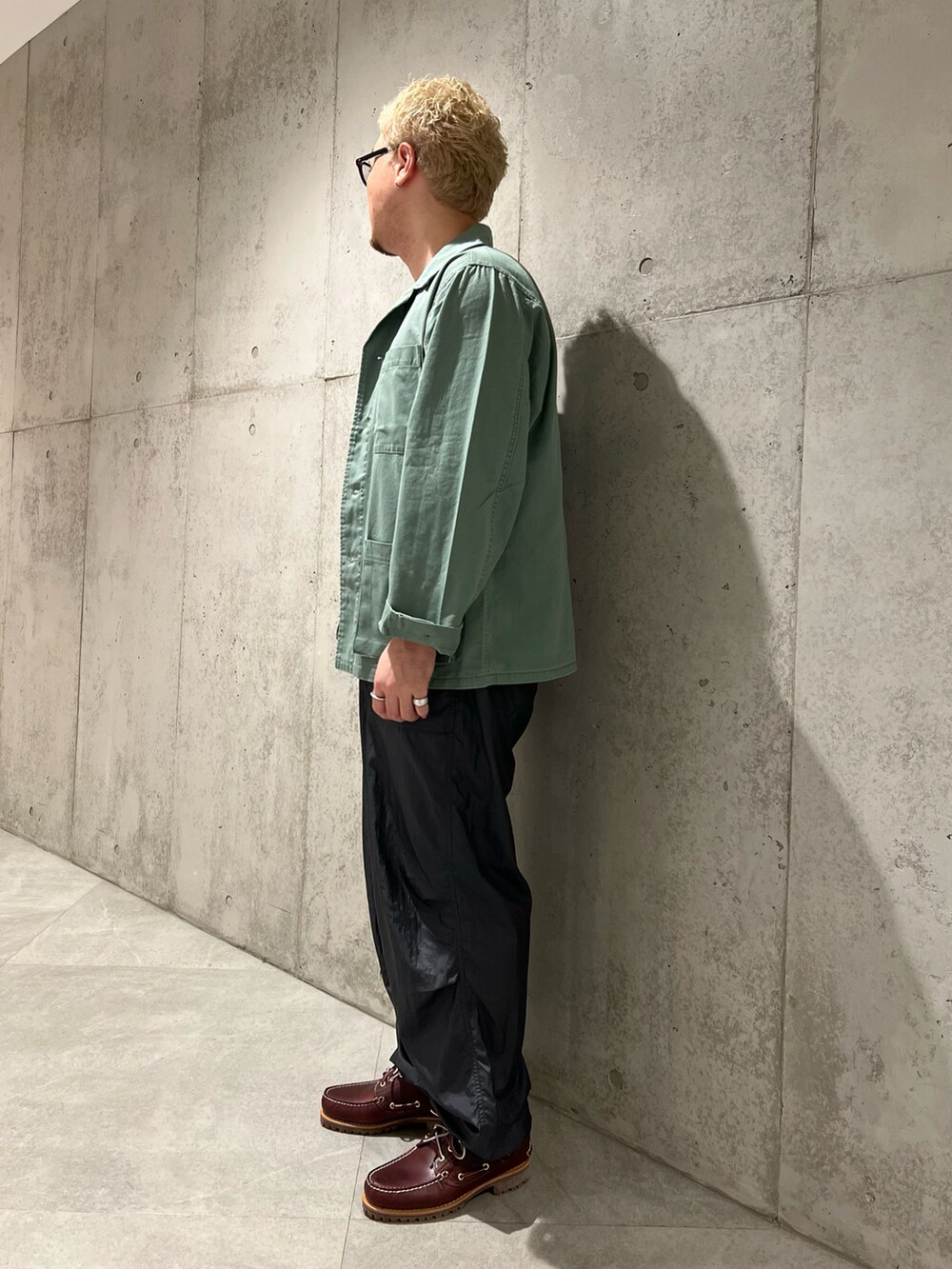 グリーン系のミリタリージャケット、グレー系のその他パンツ、レッド系のモカシン/デッキシューズを着用したメンズの秋コーディネートの2枚目の写真