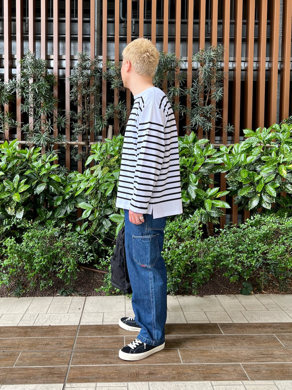 ブラック系のTシャツ/カットソー、ブルー系のデニムパンツ、ブラック系のバックパック/リュックを着用したメンズの春コーディネートの4枚目の写真