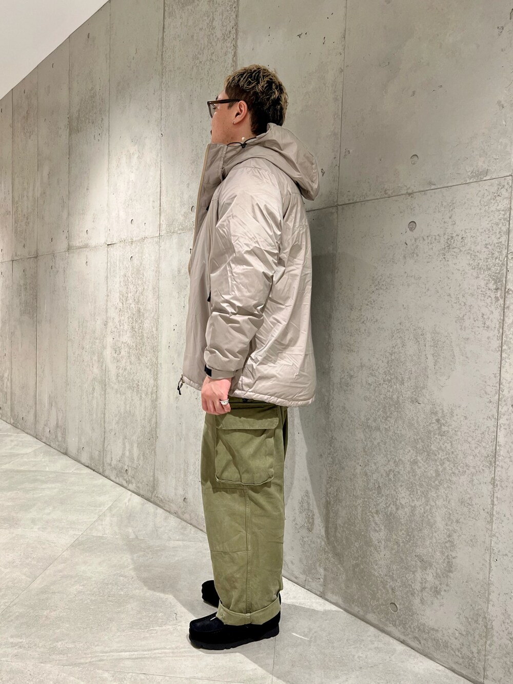 グリーン系のカーゴパンツ、ブラック系のブーツ、ベージュ系のダウンジャケット/コートを着用したメンズの秋コーディネートの3枚目の写真