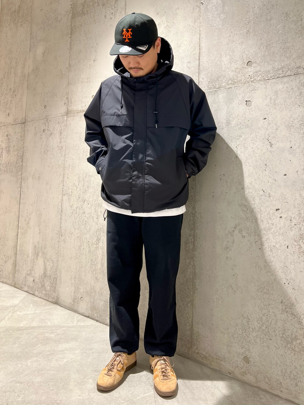 ブラック系のマウンテンパーカー、ブラック系のスウェットパンツ、レッド系のTシャツ/カットソーを着用したメンズの春コーディネートの2枚目の写真
