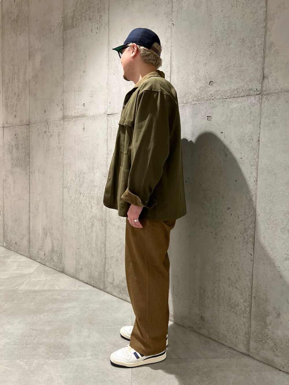 グリーン系のカバーオール、ベージュ系のTシャツ/カットソー、ブラウン系のデニムパンツを着用したメンズの秋コーディネートの2枚目の写真