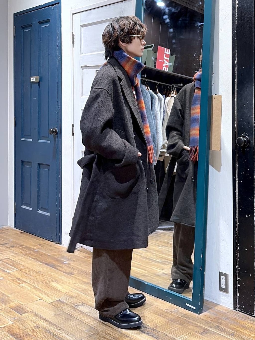 ブラック系のその他シューズ、レッド系のニット/セーター、ブラウン系のダウンジャケット/コートを着用したメンズの冬コーディネートの2枚目の写真