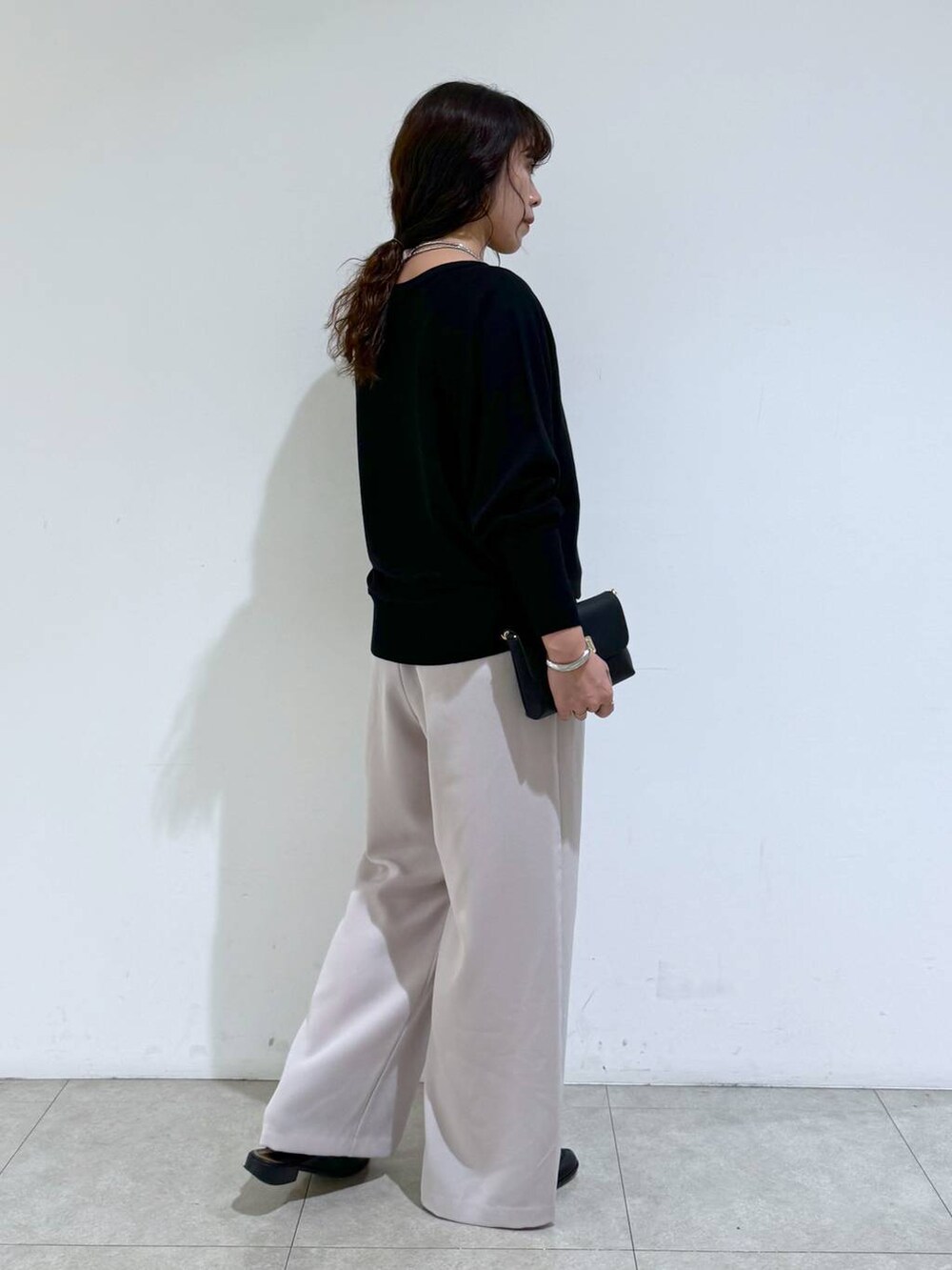 イエロー系のスラックス、ブラック系のTシャツ/カットソー、ブラック系のショルダーバッグを着用したレディースの冬コーディネートの4枚目の写真