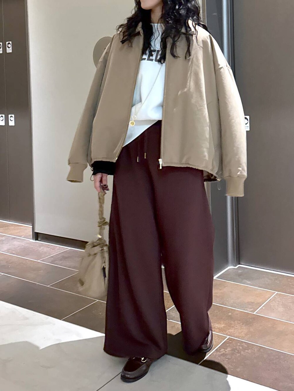 ベージュ系のブルゾン、ベージュ系のショルダーバッグ、ホワイト系のスウェットを着用したレディースの冬コーディネートの2枚目の写真