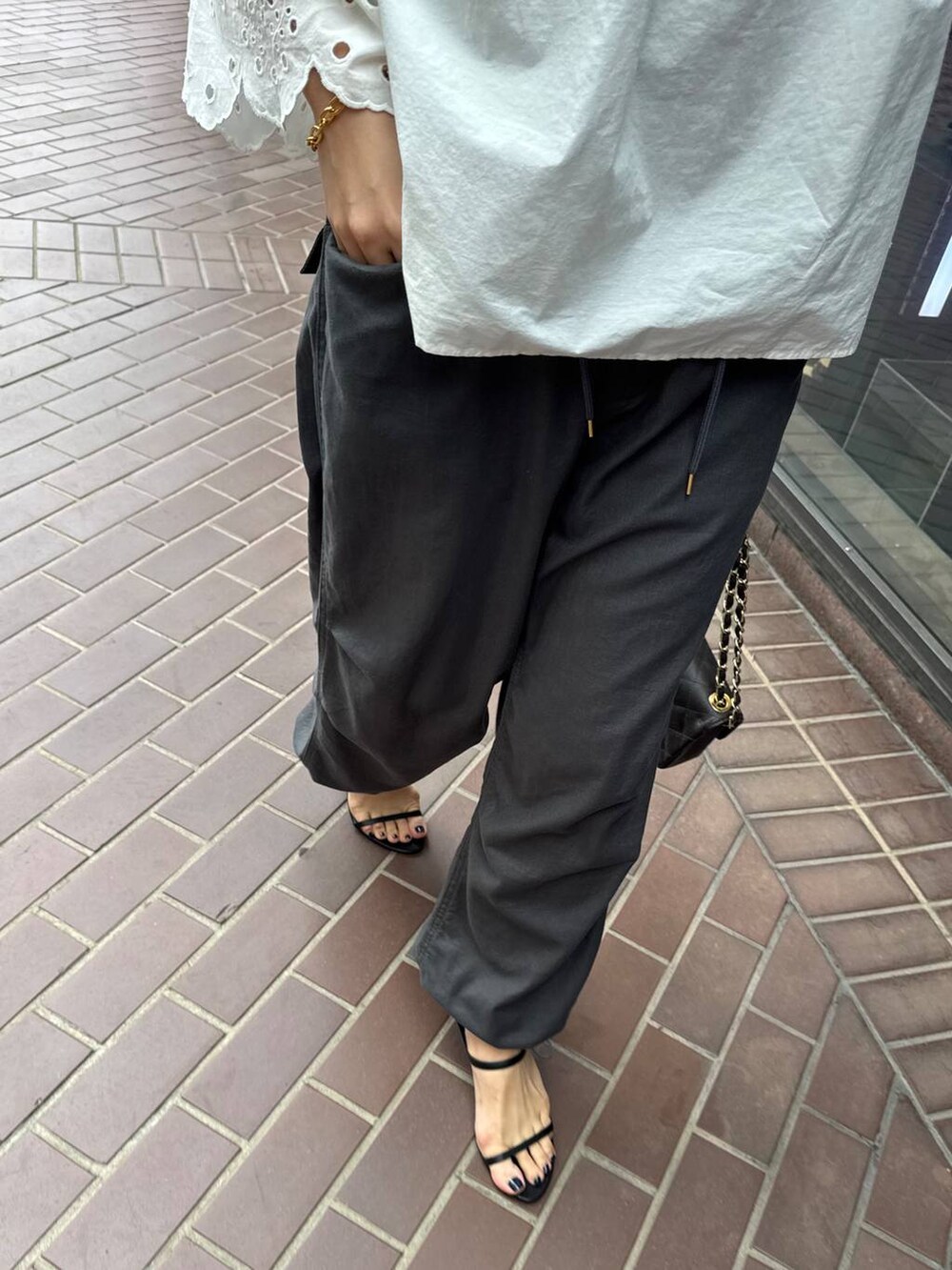 ブラウン系のハンドバッグ、ホワイト系のシャツ/ブラウス、ブラック系のサンダルを着用したレディースの春コーディネートの4枚目の写真