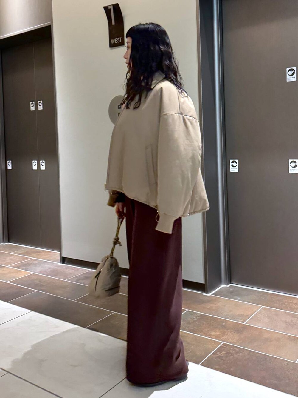 ベージュ系のブルゾン、ベージュ系のショルダーバッグ、ホワイト系のスウェットを着用したレディースの冬コーディネートの3枚目の写真