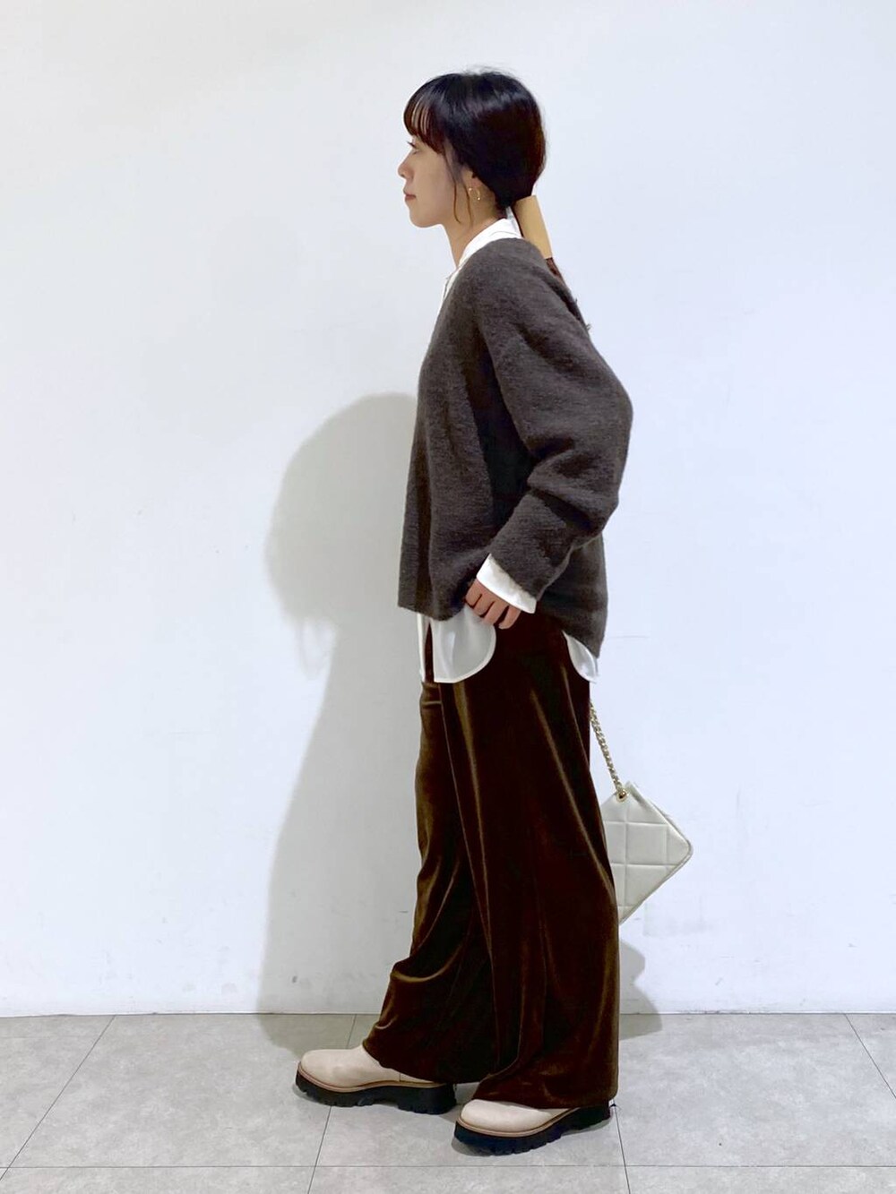 ベージュ系のブーツ、ホワイト系のショルダーバッグ、ホワイト系のシャツ/ブラウスを着用したレディースの冬コーディネートの2枚目の写真