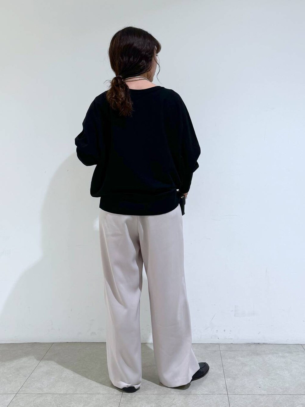 イエロー系のスラックス、ブラック系のTシャツ/カットソー、ブラック系のショルダーバッグを着用したレディースの冬コーディネートの3枚目の写真