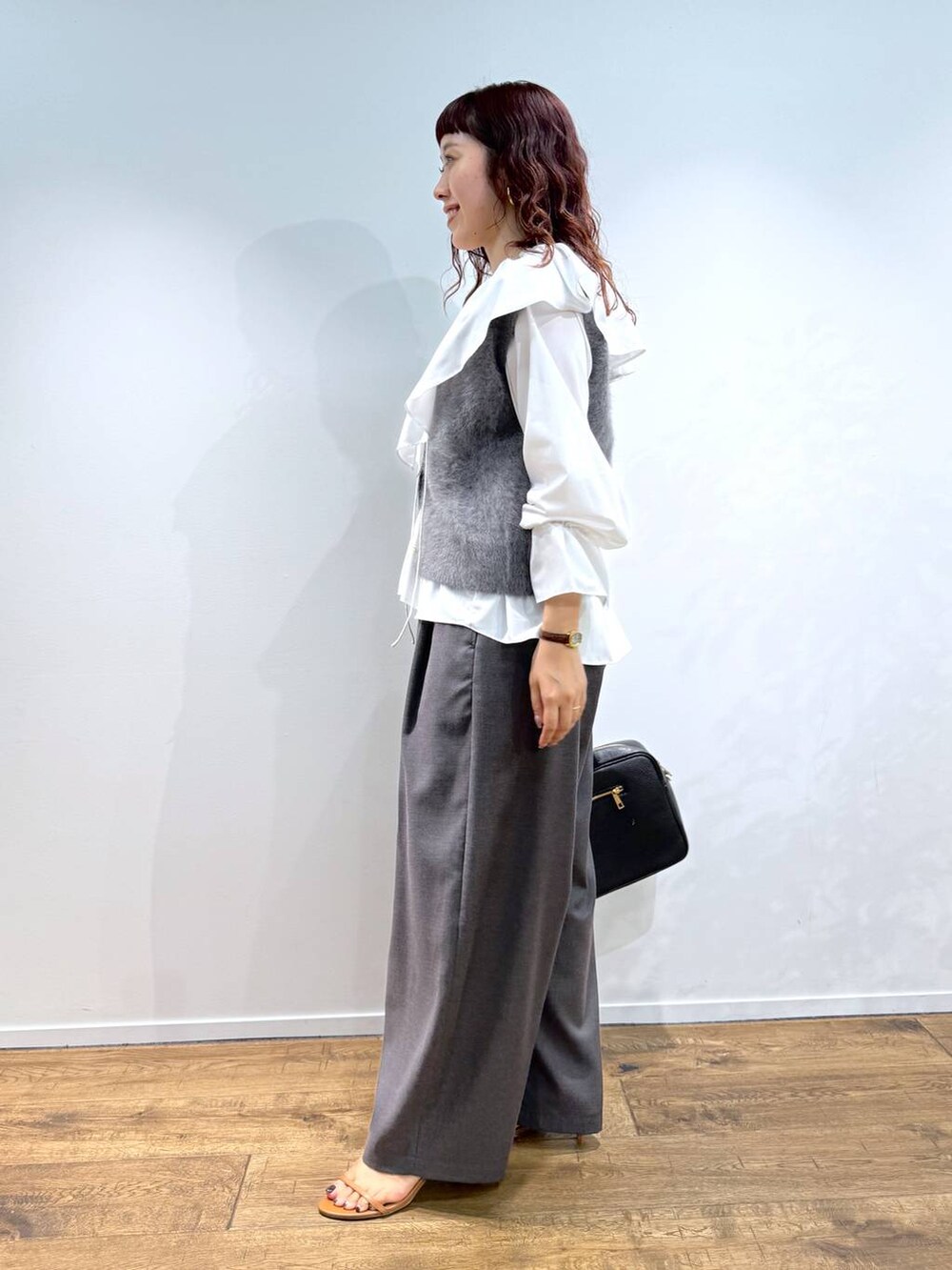 ホワイト系のシャツ/ブラウス、グレー系のベスト、ブラック系のハンドバッグを着用したレディースの夏コーディネートの2枚目の写真