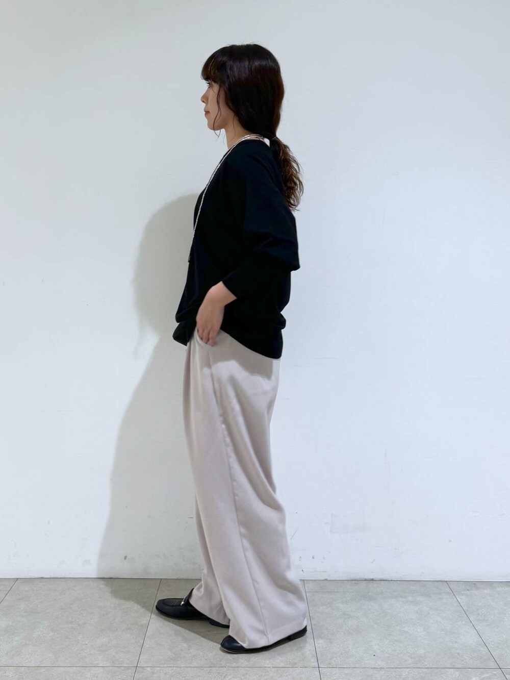 イエロー系のスラックス、ブラック系のTシャツ/カットソー、ブラック系のショルダーバッグを着用したレディースの冬コーディネートの2枚目の写真