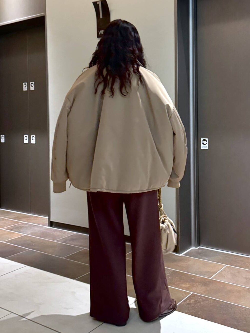 ベージュ系のブルゾン、ベージュ系のショルダーバッグ、ホワイト系のスウェットを着用したレディースの冬コーディネートの5枚目の写真