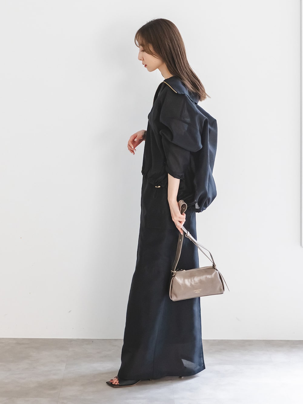 ブラック系のその他アウター、ブラック系のスカート、ブラウン系のショルダーバッグを着用したレディースの春コーディネートの2枚目の写真