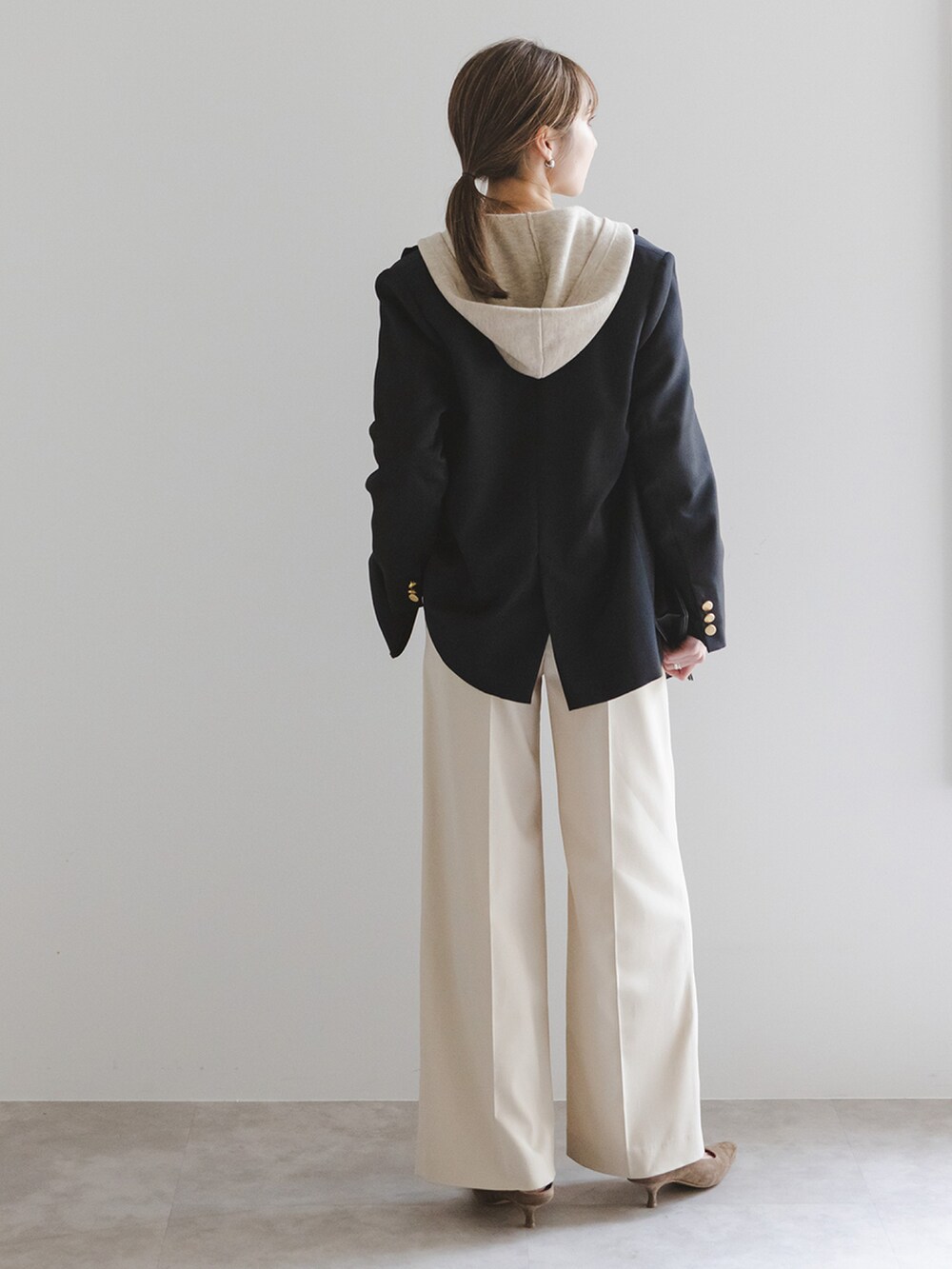 ブラック系のテーラードジャケット、ホワイト系のニット/セーター、ベージュ系のスラックスを着用したレディースの冬コーディネートの3枚目の写真